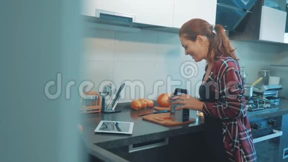那个女孩把胡萝卜揉在数字平板电脑上的烤盘上美丽的女人在烹饪和测试食物视频的预览图