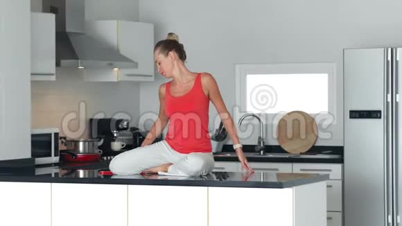 女人坐在厨房的桌子上做伸展运动放松视频的预览图