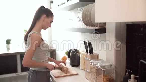 女人准备早餐切面包在厨房里视频的预览图