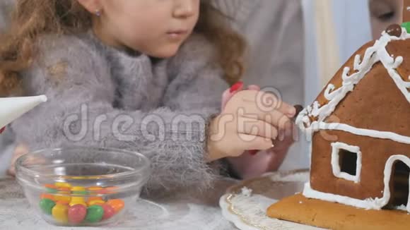 小孩子用五颜六色的糖果装饰姜饼屋视频的预览图