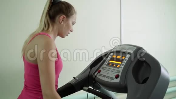 一个年轻女孩正在健身房的跑步机上工作视频的预览图
