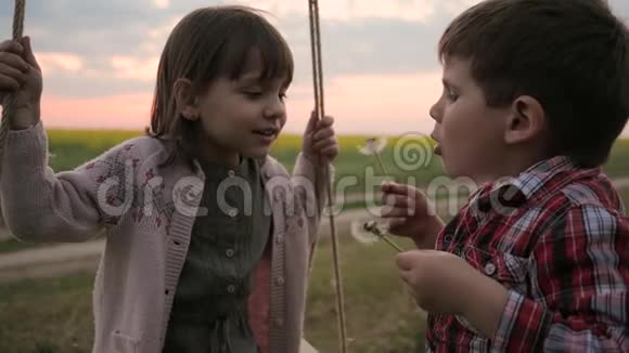 快乐的男孩和女孩双胞胎在吹球花美丽的微笑的孩子们在公园玩耍孩子吹视频的预览图