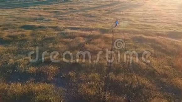 在日落的天空背景下乡村地区的年轻女子骑自行车视频的预览图