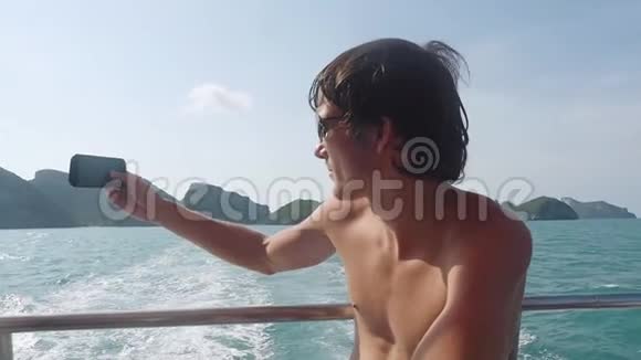 年轻的帅哥戴着太阳镜在海上航行时拍照人们旅行的概念慢动作视频的预览图