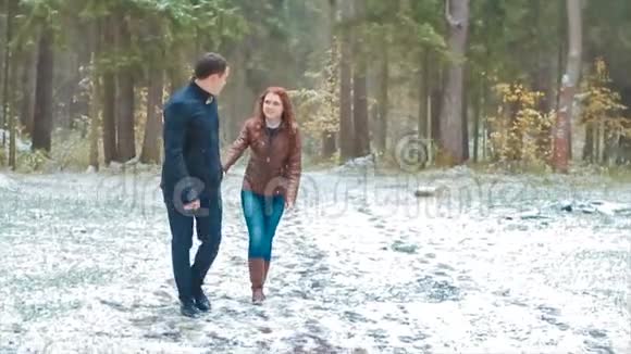 一对冬雪针叶林散步男女牵手在雪地公园慢动作视频的预览图