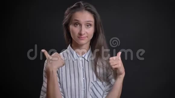 年轻的白种人长发女子的肖像用手指示意以表示喜欢和尊重的黑色背景视频的预览图
