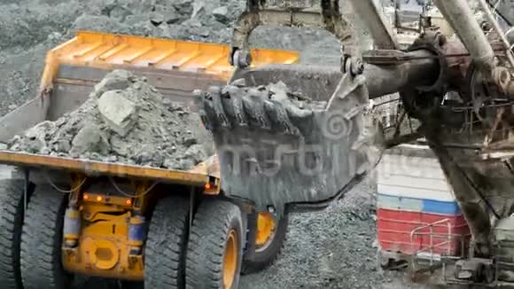 挖掘机装满自卸汽车斗式挖掘机在挖掘或建造中将石块装入自卸汽车车身视频的预览图