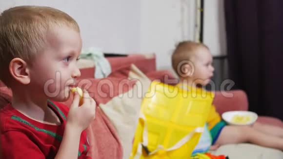 兄弟们坐在家里的沙发上看电视吃玉米棒微笑视频的预览图