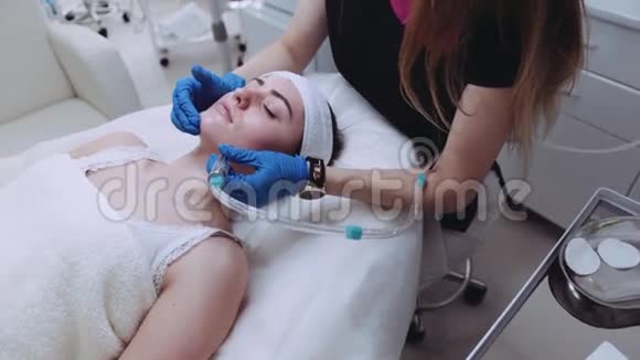 专业美容师为美丽的女性患者做面部真空按摩复兴程序视频的预览图
