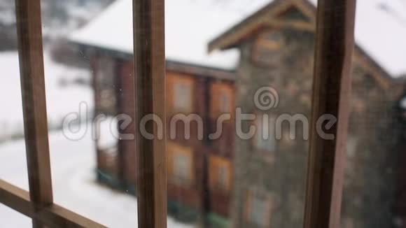 在大雪期间透过窗户观看山村的木屋落在木屋上的雪视频的预览图