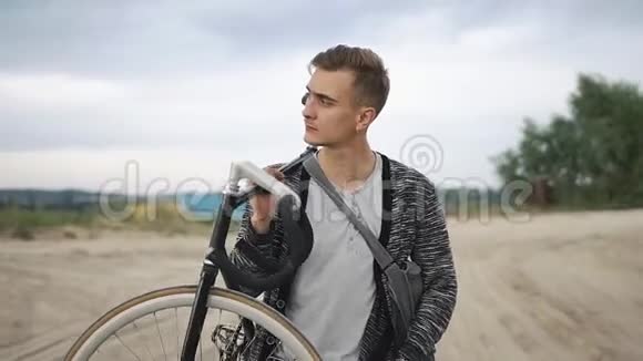 人走路时肩膀上骑自行车他沿着湖边的沙路走视频的预览图