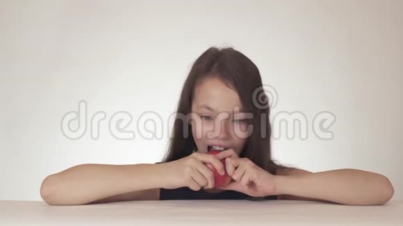 美丽快乐的少女胃口大开喜欢在白色的背景下吃红的新鲜的美味的苹果视频的预览图