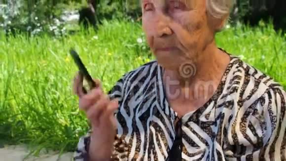 有电话的成熟女人一位退休妇女正在公园里用手机说话戴墨镜的老妇人视频的预览图