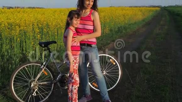 一个带着孩子看日落的女人有自行车的体育家庭妈妈拥抱她的女儿视频的预览图