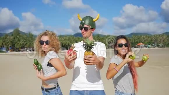 三个无忧无虑的年轻朋友在海滩上闲逛和异国情调的泰国水果跳舞纯素舞蹈泰国范甘视频的预览图