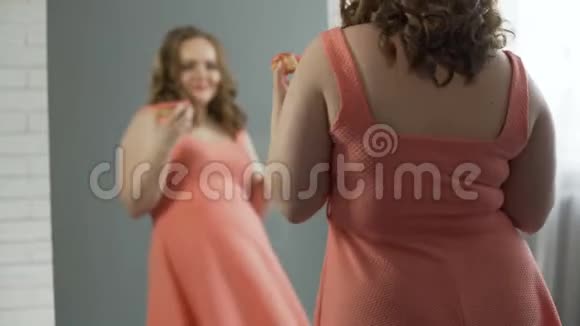 在镜子前吃甜甜圈的超大身材女孩感到高兴和满意视频的预览图