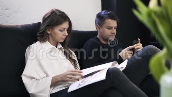 年轻夫妇在沙发上看杂志视频的预览图