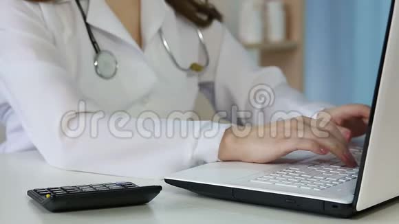 女医生在笔记本电脑上填写健康保险表格计算费用视频的预览图