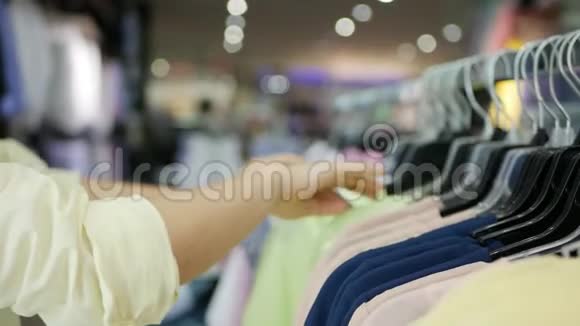 年轻女子店里挑选衬衫的侧视视频的预览图