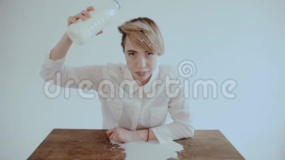 充满激情的年轻女人卷发手里拿着金瓶子张开嘴把白色酸奶倒在脸上视频的预览图
