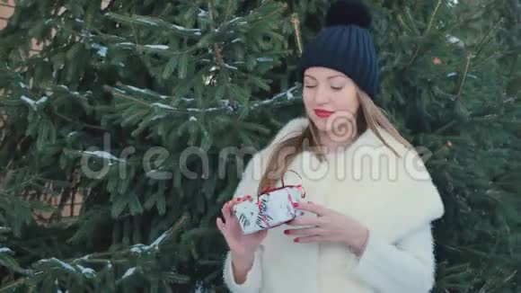 红唇美女在杉树背景下捧着节日礼物视频的预览图
