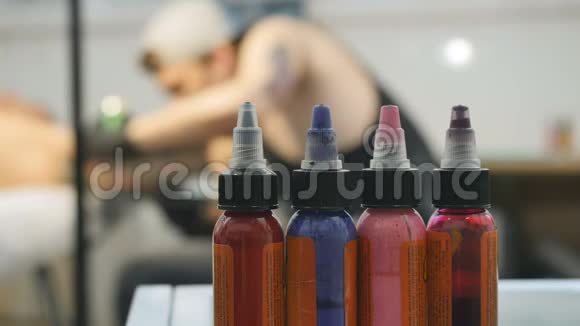 有彩色颜料的瓶子纹身师正在处理模糊的背景视频的预览图