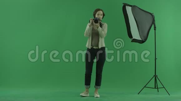 一位年轻女子在绿色屏幕上为观众拍照并纠正他的站立姿势视频的预览图