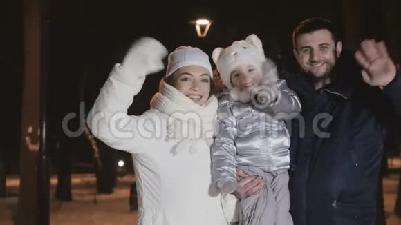 幸福的家庭在傍晚的冬季公园挥手视频的预览图