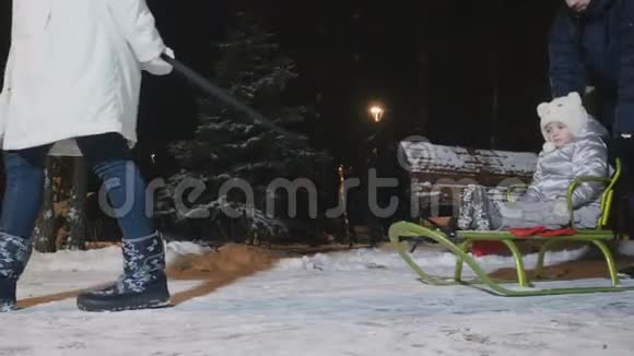 在冬天的傍晚父母把小女儿卷在雪橇上视频的预览图