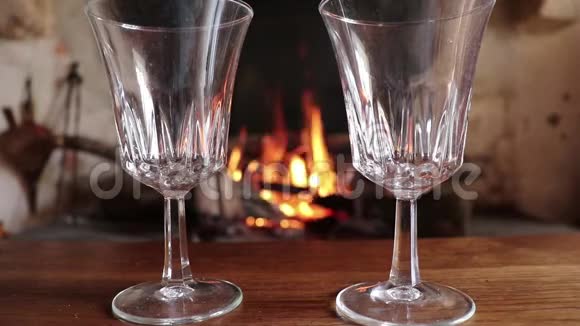 在燃烧的壁炉背景上放满了白酒的两杯视频的预览图