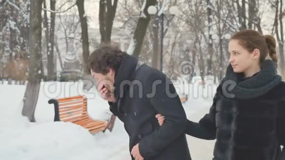 打喷嚏的男人和漂亮的女人在冬天的公园里喷鼻子视频的预览图