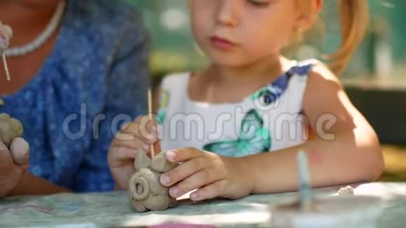 一个小女孩在祖母的帮助下雕刻泥塑视频的预览图