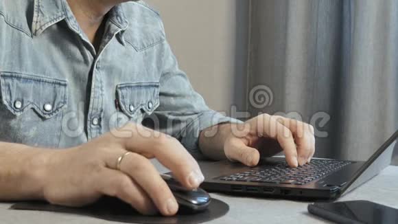 男性手在笔记本电脑的键盘上打字特写镜头自由职业者在家工作视频的预览图