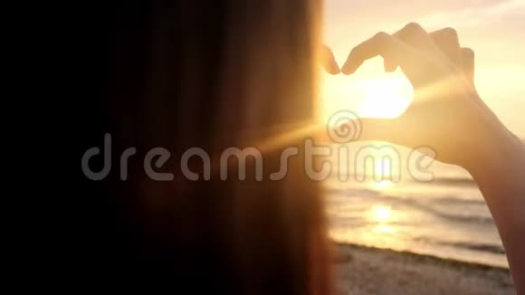 下面的动作结束无法辨认的女人用她心形的手指捕捉夕阳年轻的女孩视频的预览图