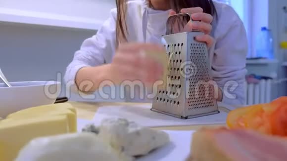 在厨房里女人在家里的烤架上擦奶酪双手特写视频的预览图