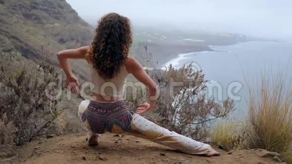 一个女人坐在悬崖边上摆出一副俯瞰大海的姿势举起双手吸气视频的预览图