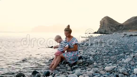 晚上好海边儿子坐在母亲腿上吃水果和浆果视频的预览图