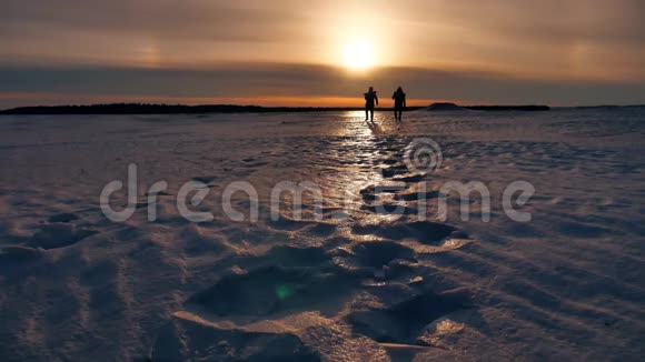 两个男子剪影的日落徒步旅行者走在阳光下未触及的雪景冒险旅程视频的预览图