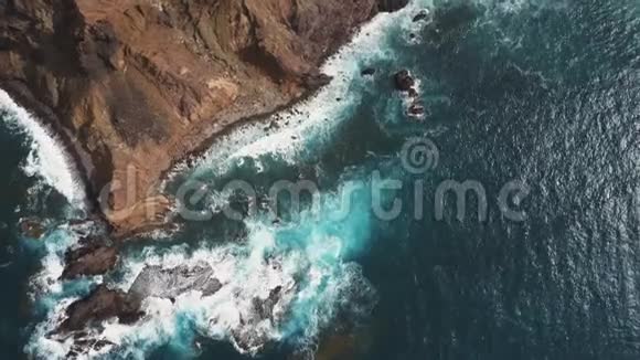 海浪在岩石上破碎的空中俯视西班牙加那利群岛特内里费的蓝水和白色泡沫视频的预览图