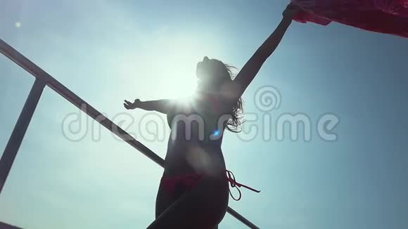 穿着比基尼的年轻美女站着双手伸直帕雷奥感觉到夏日的微风在开阔的大海上航行视频的预览图