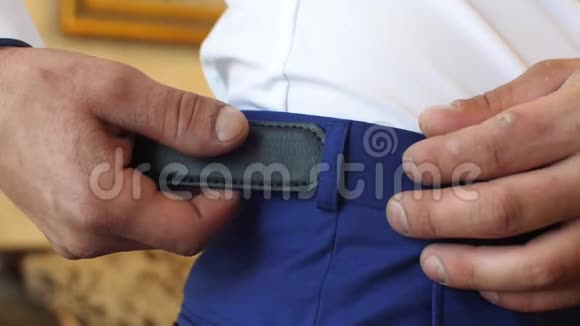 男人的手收紧时髦的皮带在男人的裤子上有闪亮的扣特写镜头视频的预览图