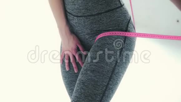 一个年轻的运动女孩的身体她侧身站立测量臀部腰部的体积视频的预览图