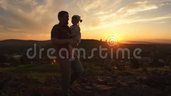 一个幸福的家庭在日落时父亲正把女儿抱在怀里视频的预览图