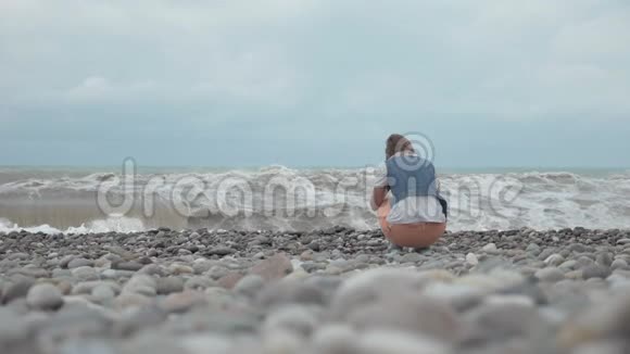 海滩上的年轻女孩看着大海的巨浪乔治亚视频的预览图