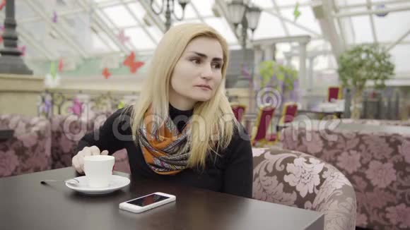 带着智能手机和咖啡的悲伤女人视频的预览图