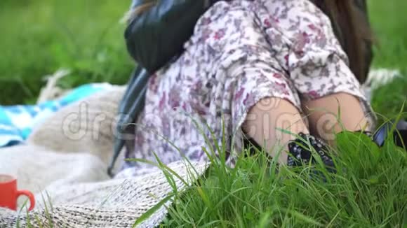 一个女孩坐在河边的草地上喝热茶视频的预览图