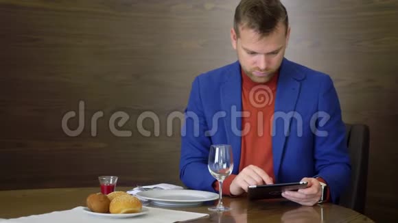帅哥在餐厅就餐在等待点餐时使用平板电脑视频的预览图