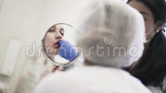 在沙龙里注射嘴唇后照镜子的女人视频的预览图