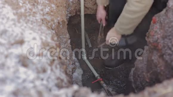人类在地球上的一个洞里对水系统进行紧急修理用灰色塑料管工作的水管视频的预览图