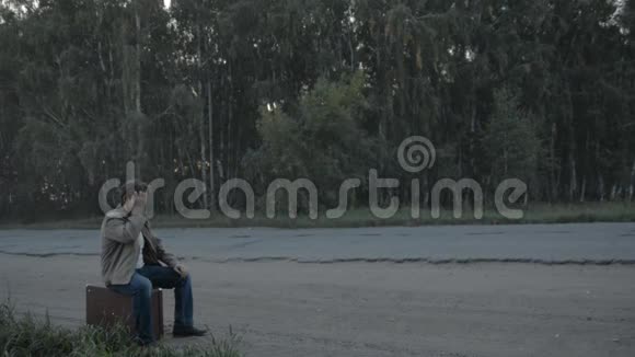 一个提箱的旅行者在乡间小路上跛行视频的预览图